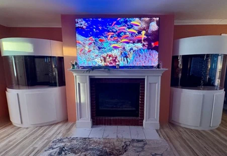 Custom aquarium installation with reef tank above fireplace and side tanks